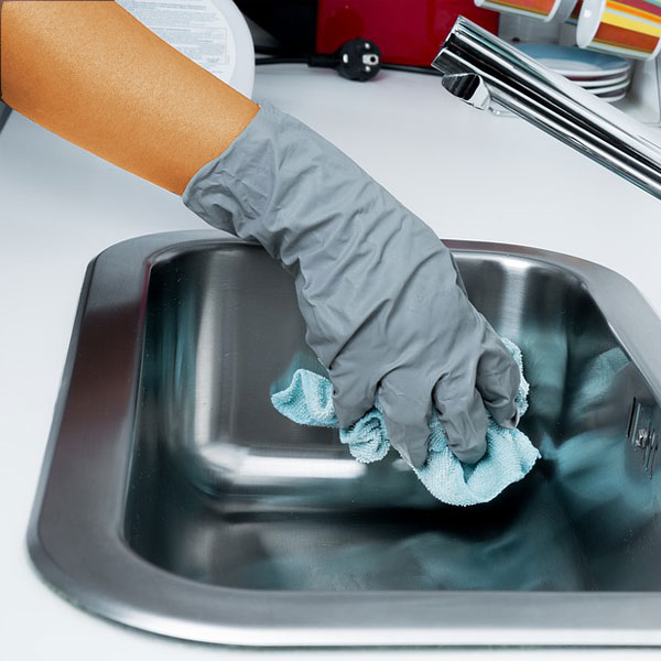 One of the many cleaning Services offered by No Boundaries Care Services a person cleaning a kitchen sink.